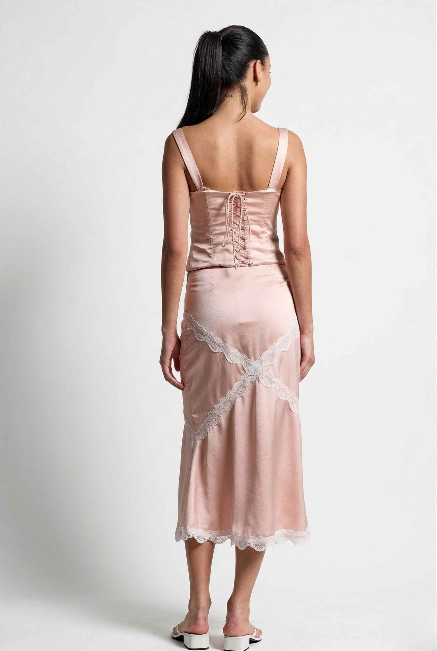 Woman wearing a Sophie Top Pink Pastel Satin Corset Cami with White Lace Trim with lace details on a white background