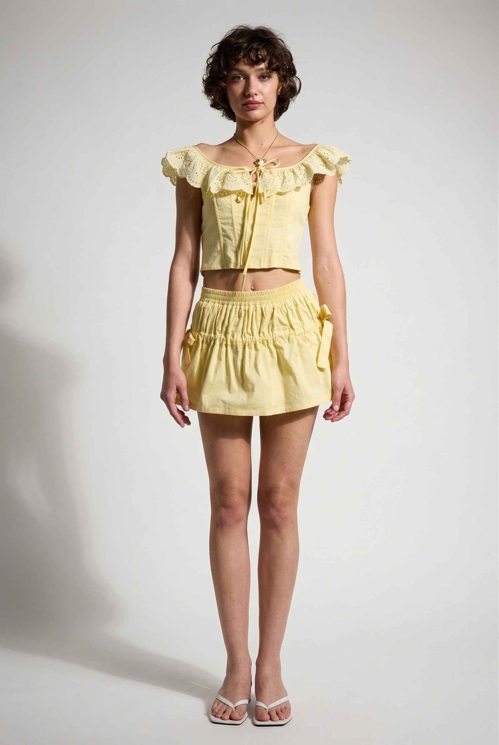 Sunnie Skirt in Soft Yellow Poplin Mini Skirt with Bows paired with matching ruffle top and slip-on sandals