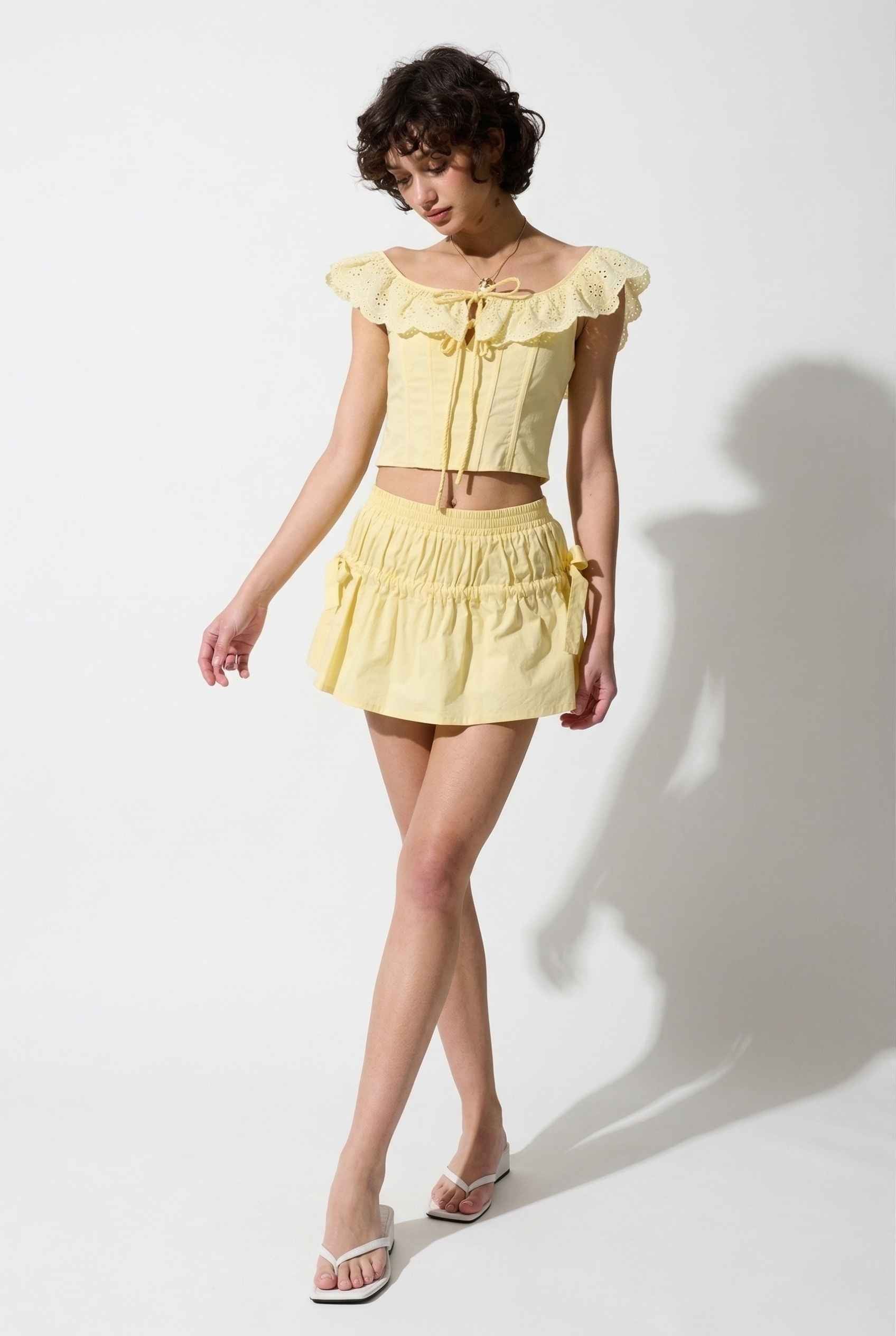 Sunnie Skirt in Soft Yellow Poplin Mini Skirt with Bows paired with matching ruffle top and slip-on sandals