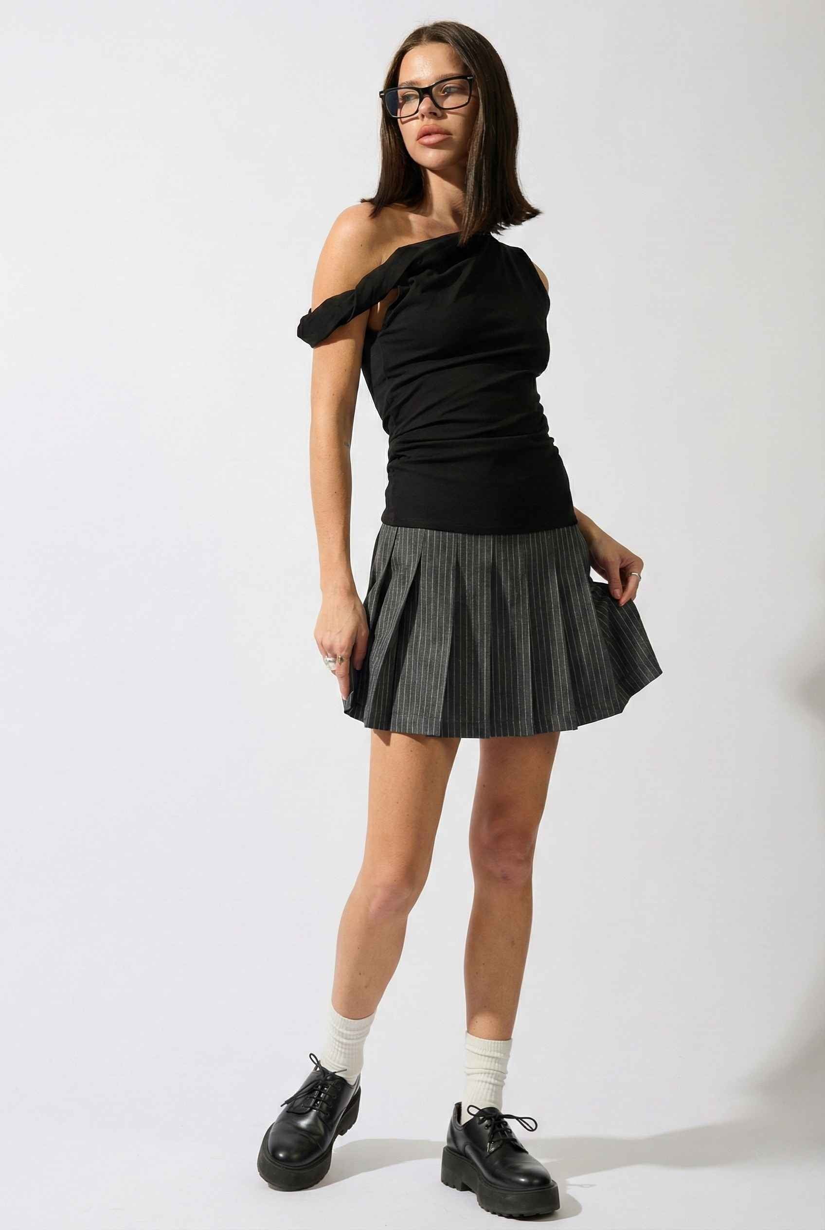 Woman wearing a Sutton Mini Black Asymmetrical Knit & Pinstripe Dress on a white background