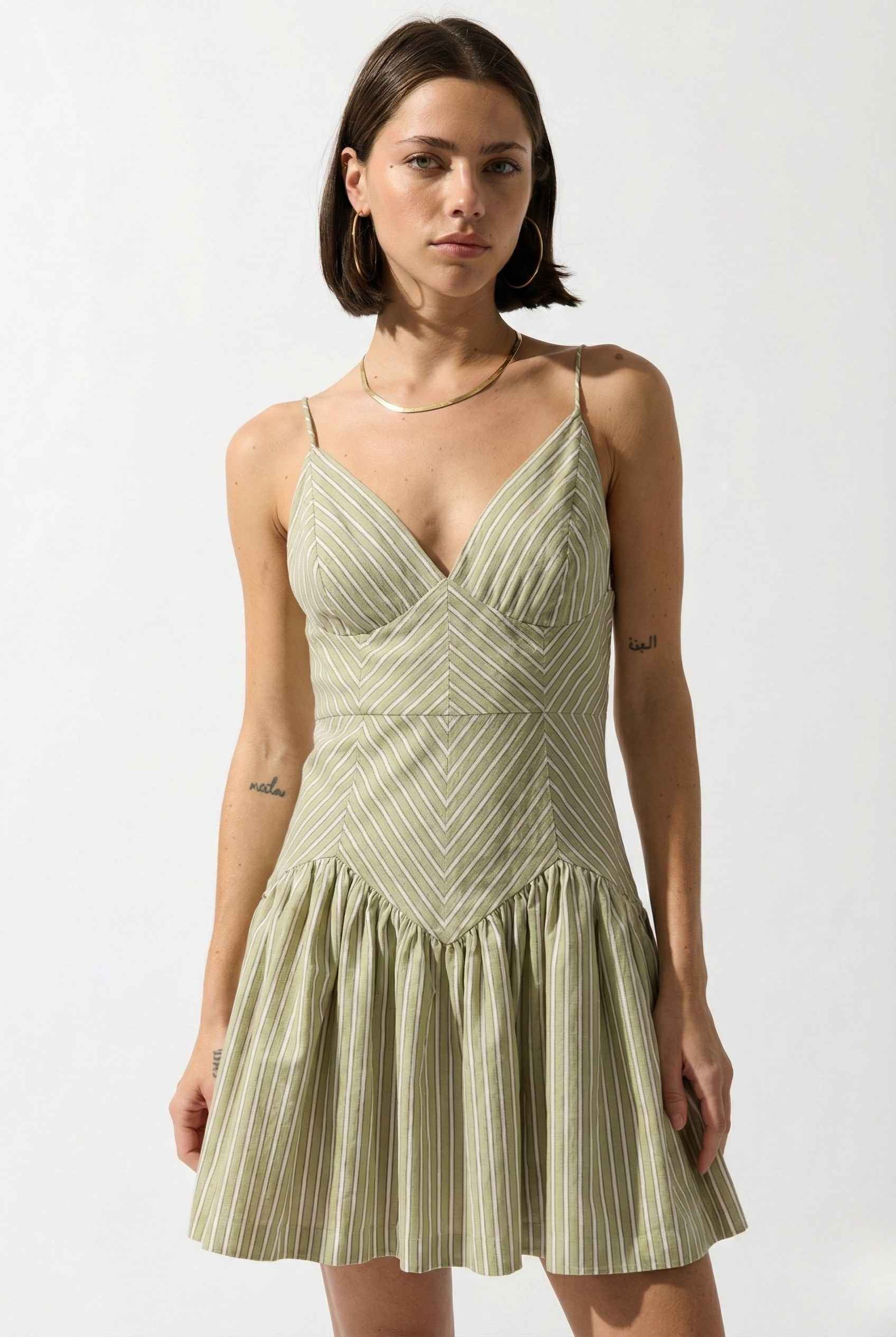 Woman wearing a Sutton Mini Sage Stripe Drop Waist Cotton Dress against a white background