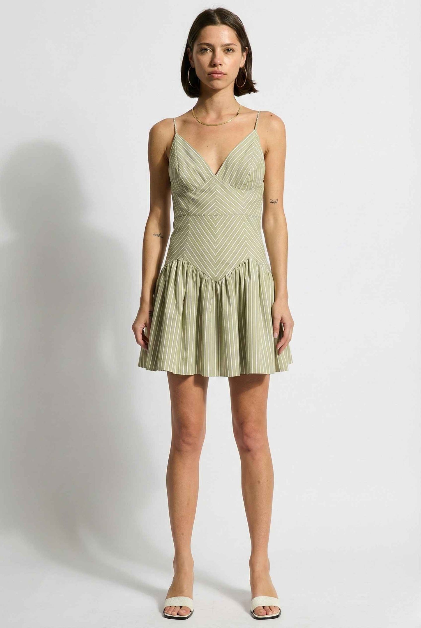 Woman wearing a Sutton Mini Sage Stripe Drop Waist Cotton Dress against a white background