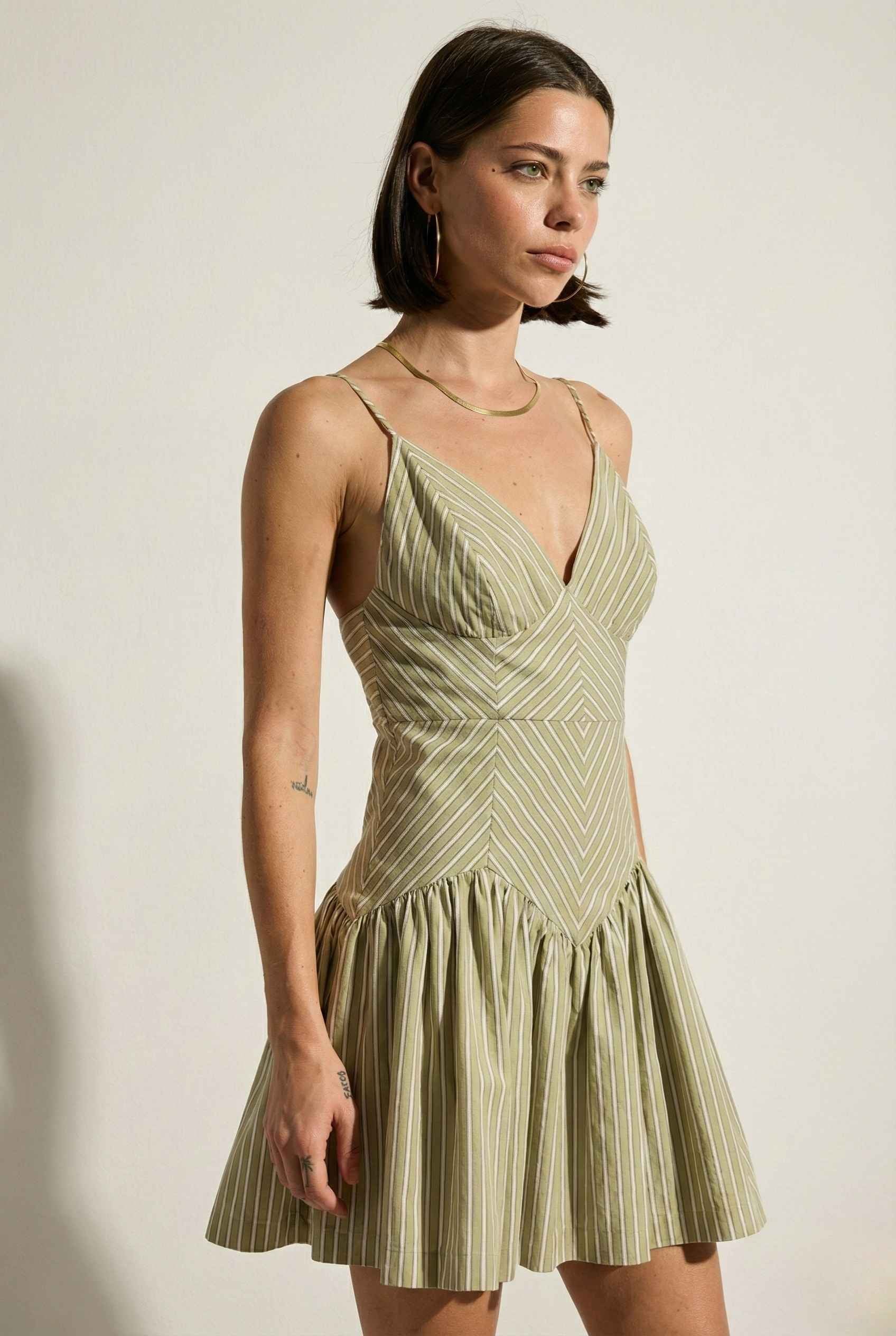 Woman wearing a Sutton Mini Sage Stripe Drop Waist Cotton Dress against a plain background