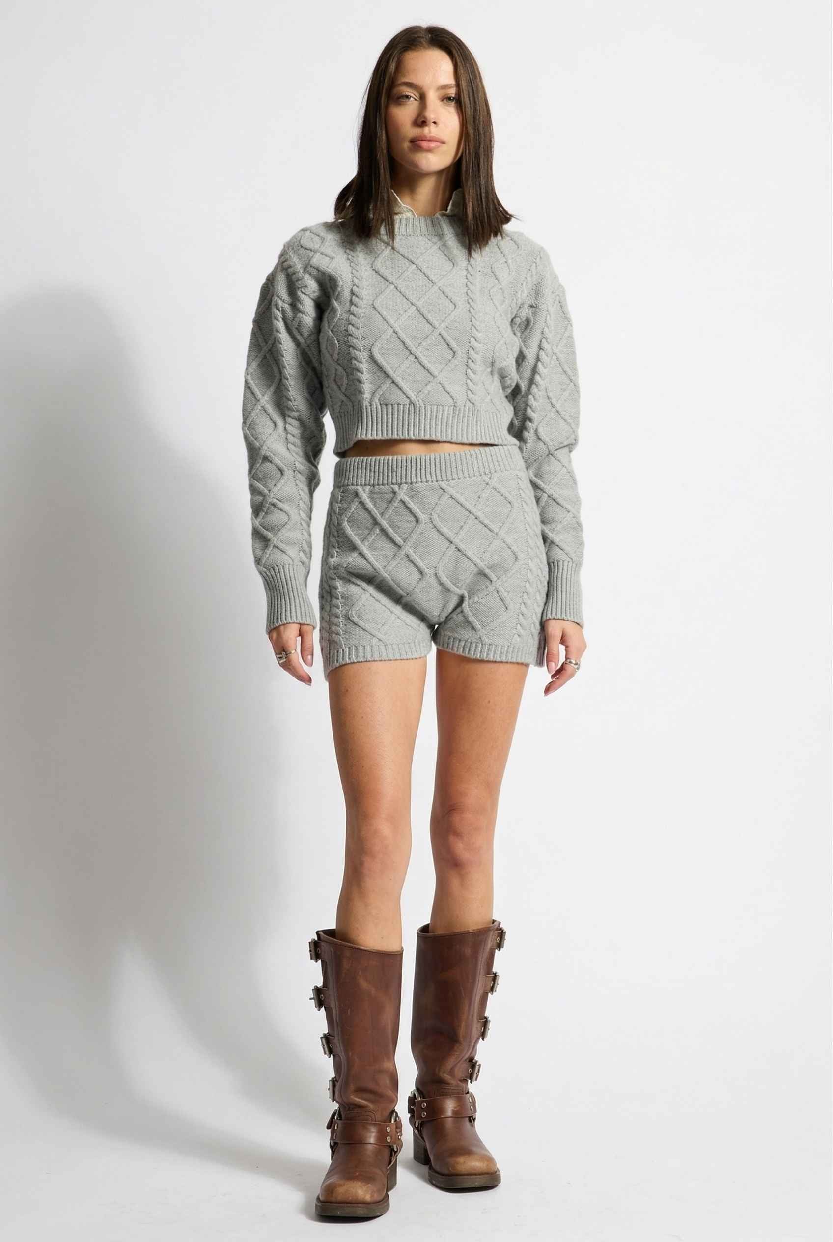 Model wearing Sutton Shorts in Grey Cable Knit High-Waist Lounge Shorts paired with matching crop sweater and knee-high riding boots