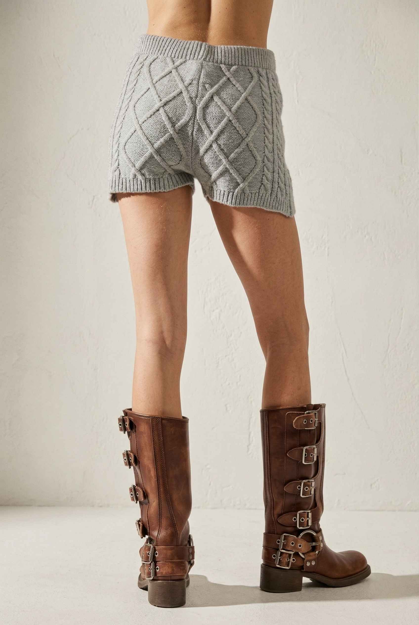 Model wearing Sutton Shorts in Grey Cable Knit High-Waist Lounge Shorts paired with matching crop sweater and knee-high riding boots