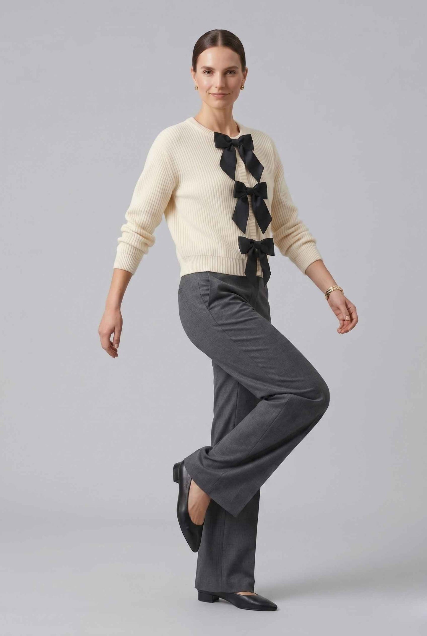 Woman wearing The Camille Bow Cardigan Ribbed Shaker Cream Knit Sweater on a plain background