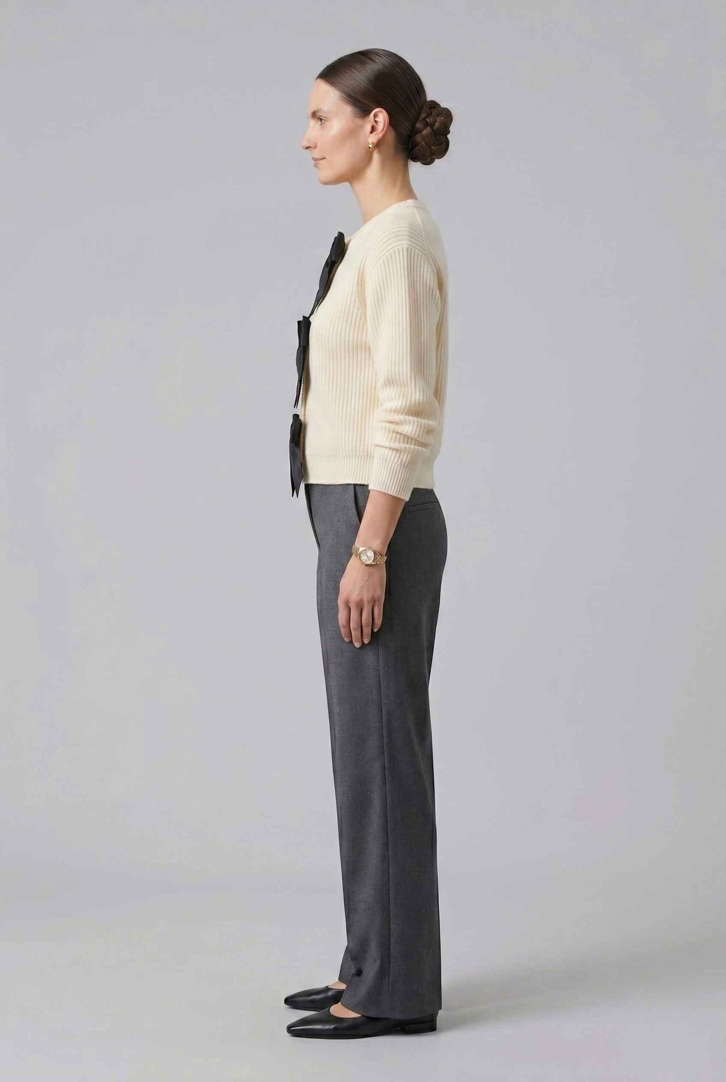 Woman wearing The Camille Bow Cardigan Ribbed Shaker Cream Knit Sweater on a plain background