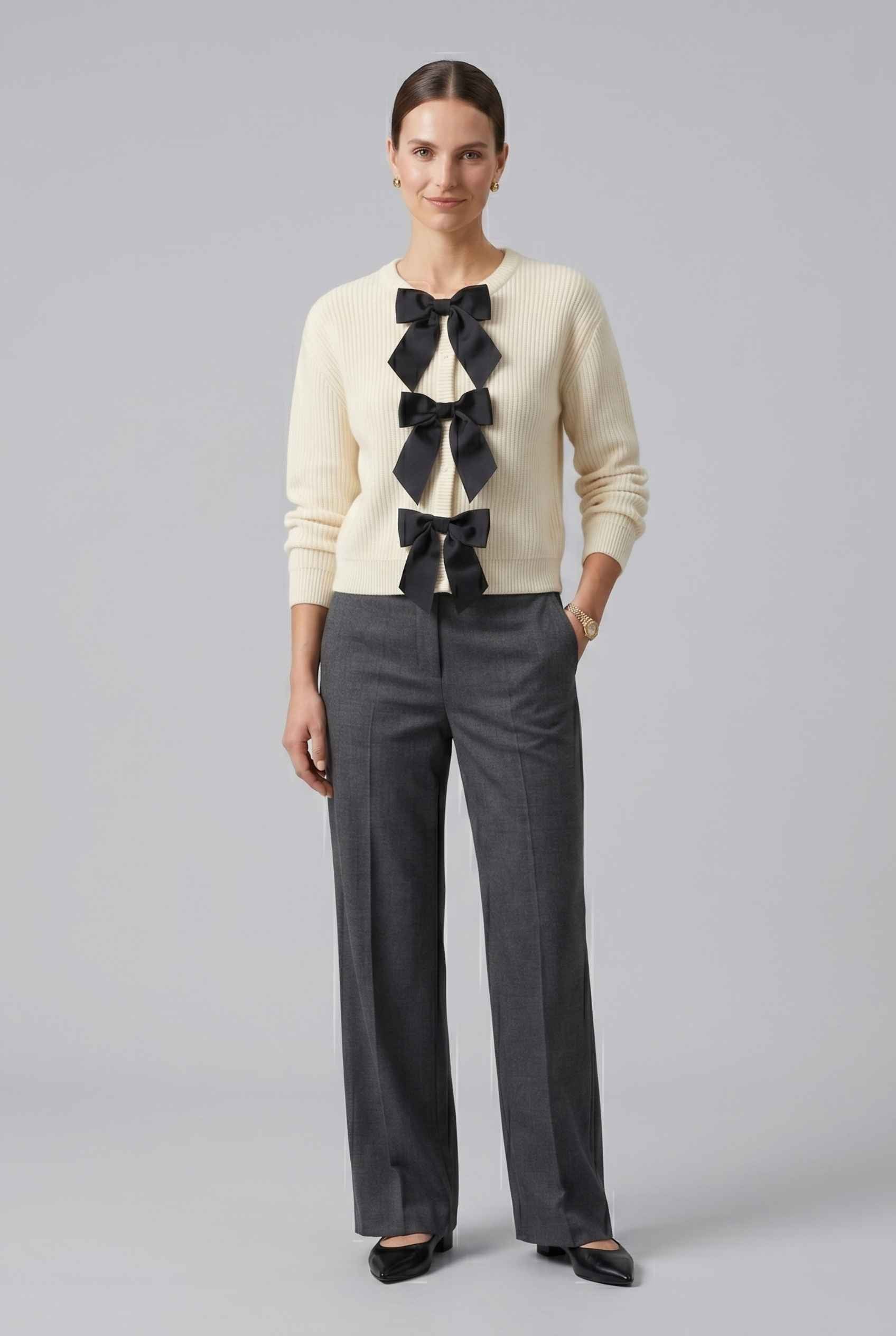 Woman wearing The Camille Bow Cardigan Ribbed Shaker Cream Knit Sweater on a light gray background