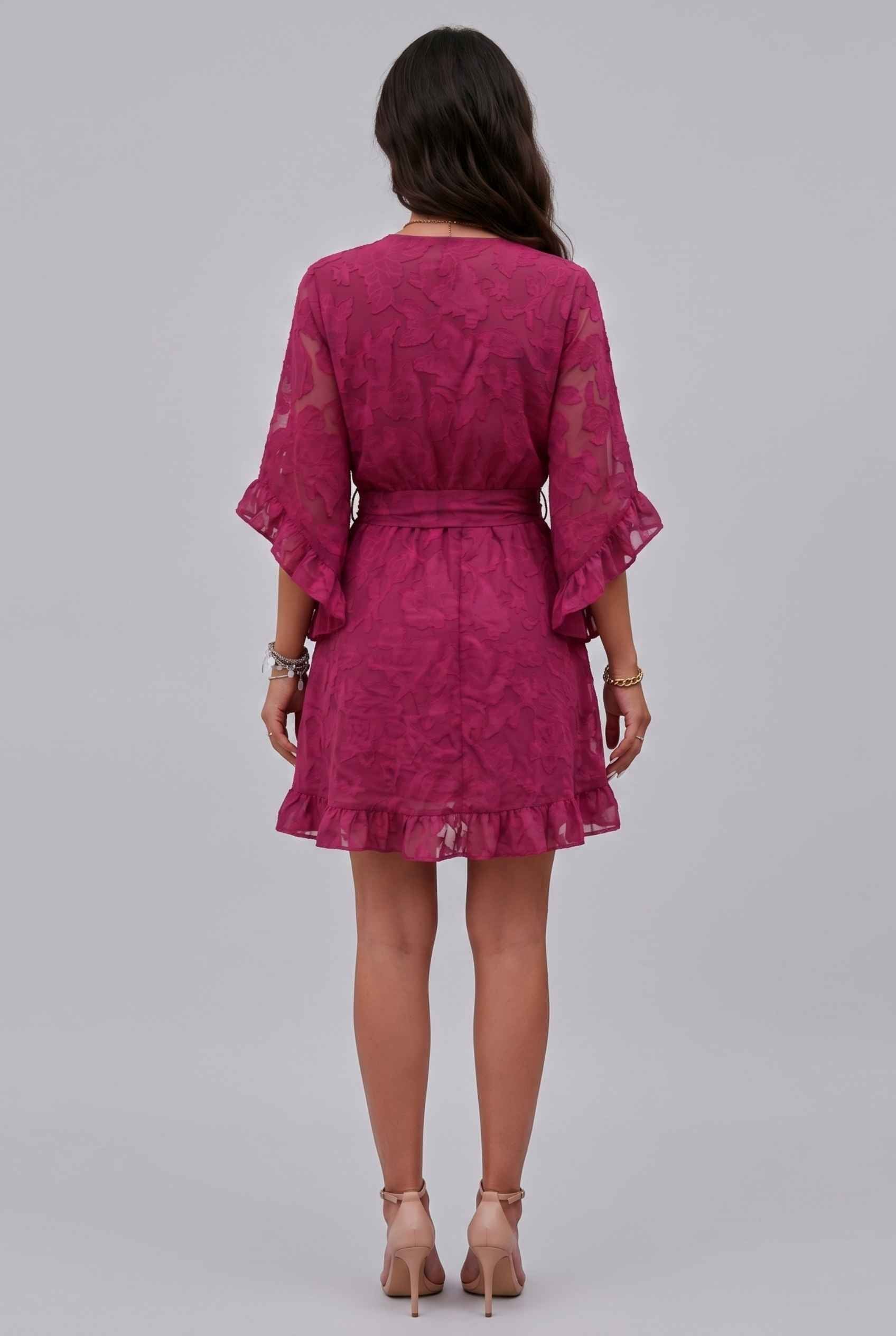Woman wearing The Cherise Devoré Wrap Dress Jacquard Floral Lace Pink Mini Dress on a gray background