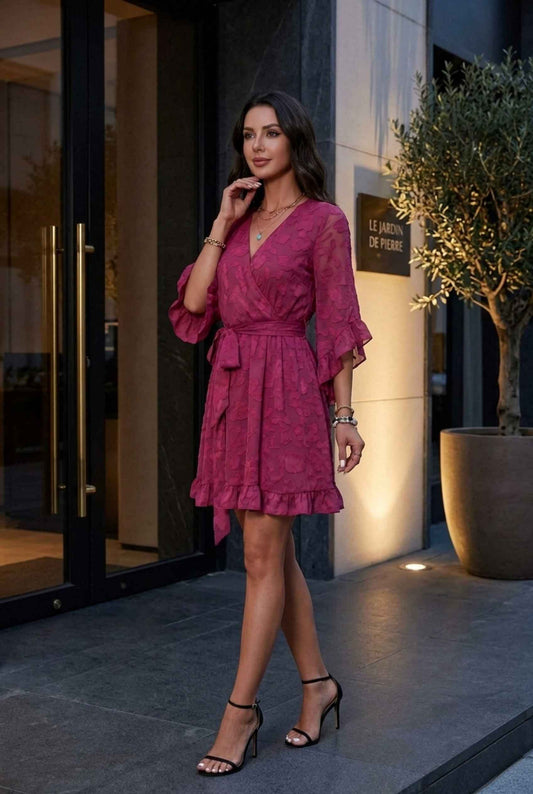 Woman wearing The Cherise Devoré Wrap Dress Jacquard Floral Lace Pink Mini Dress with strappy heels standing outside of luxury restaurant in the evening time