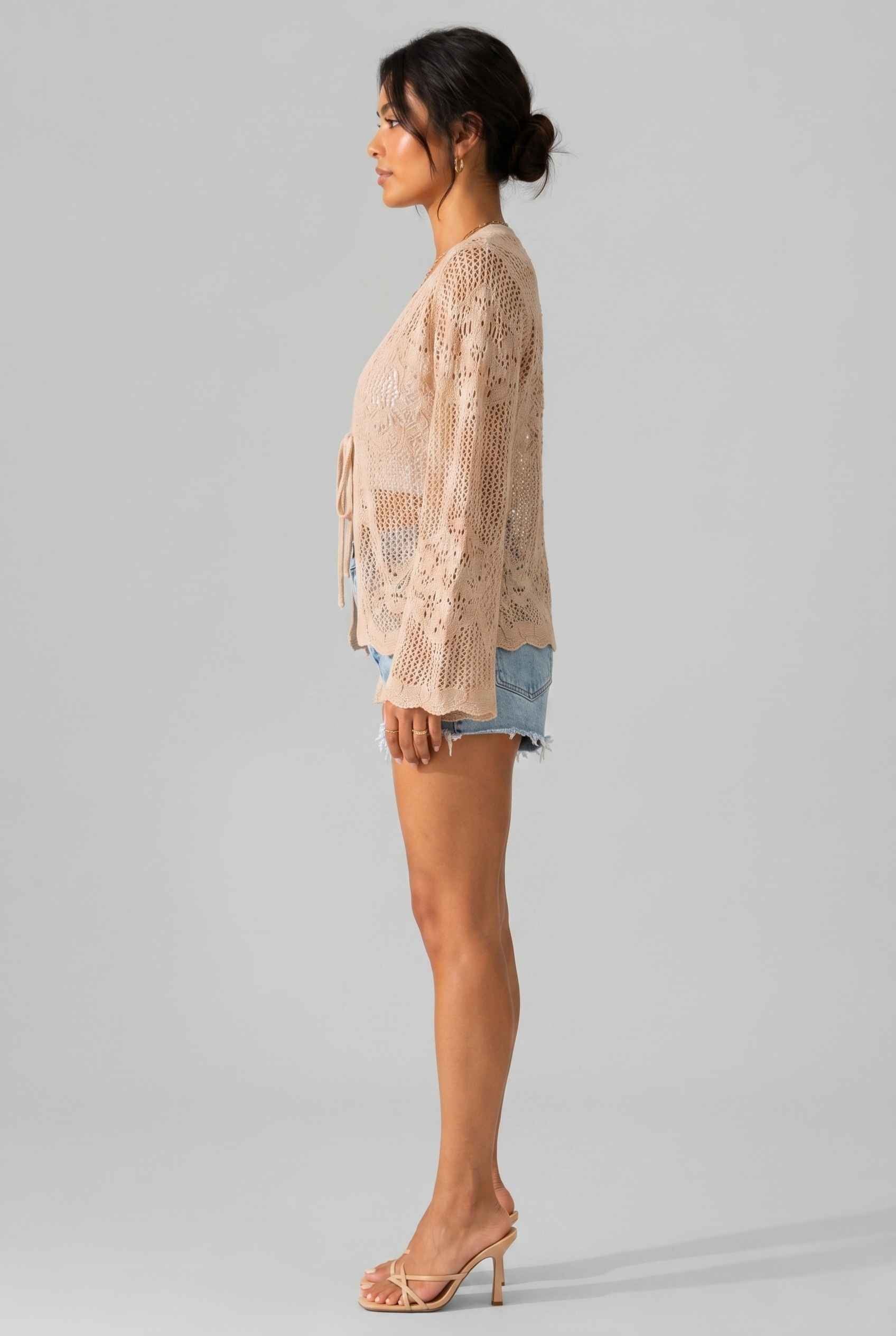 Woman wearing The Faye Tie-Front Cardigan Open Stitch Beige Crochet Cardigan on a gray background