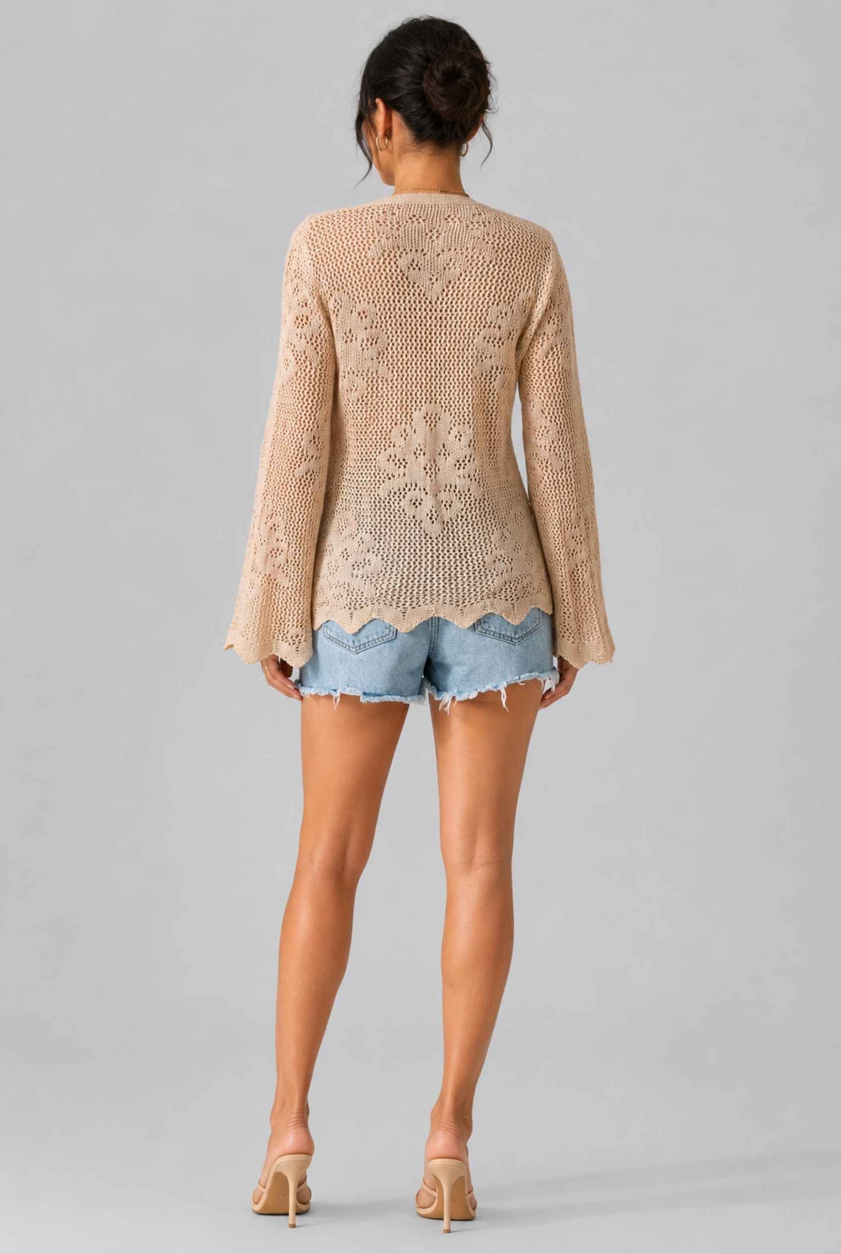 Woman wearing The Faye Tie-Front Cardigan Open Stitch Beige Crochet Cardigan on a gray background