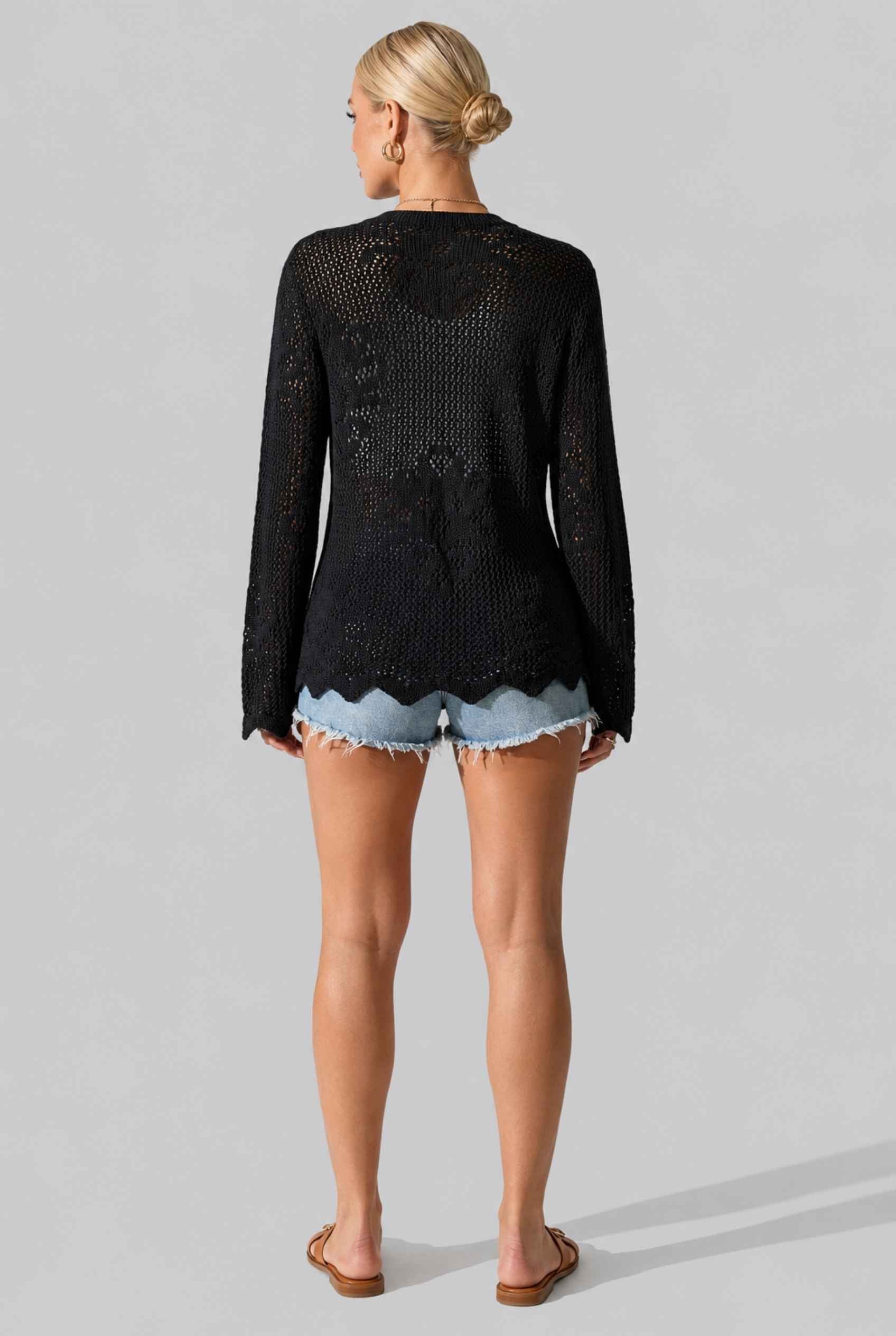 Woman wearing The Faye Tie-Front Cardigan Open Stitch Black Crochet Cardigan on a gray background
