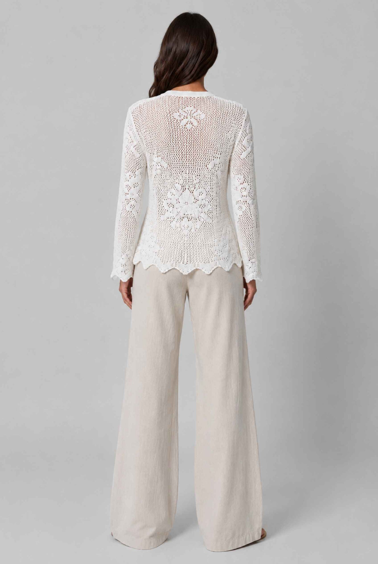 Woman wearing The Faye Tie-Front Cardigan Open Stitch White Crochet Cardigan on a gray background