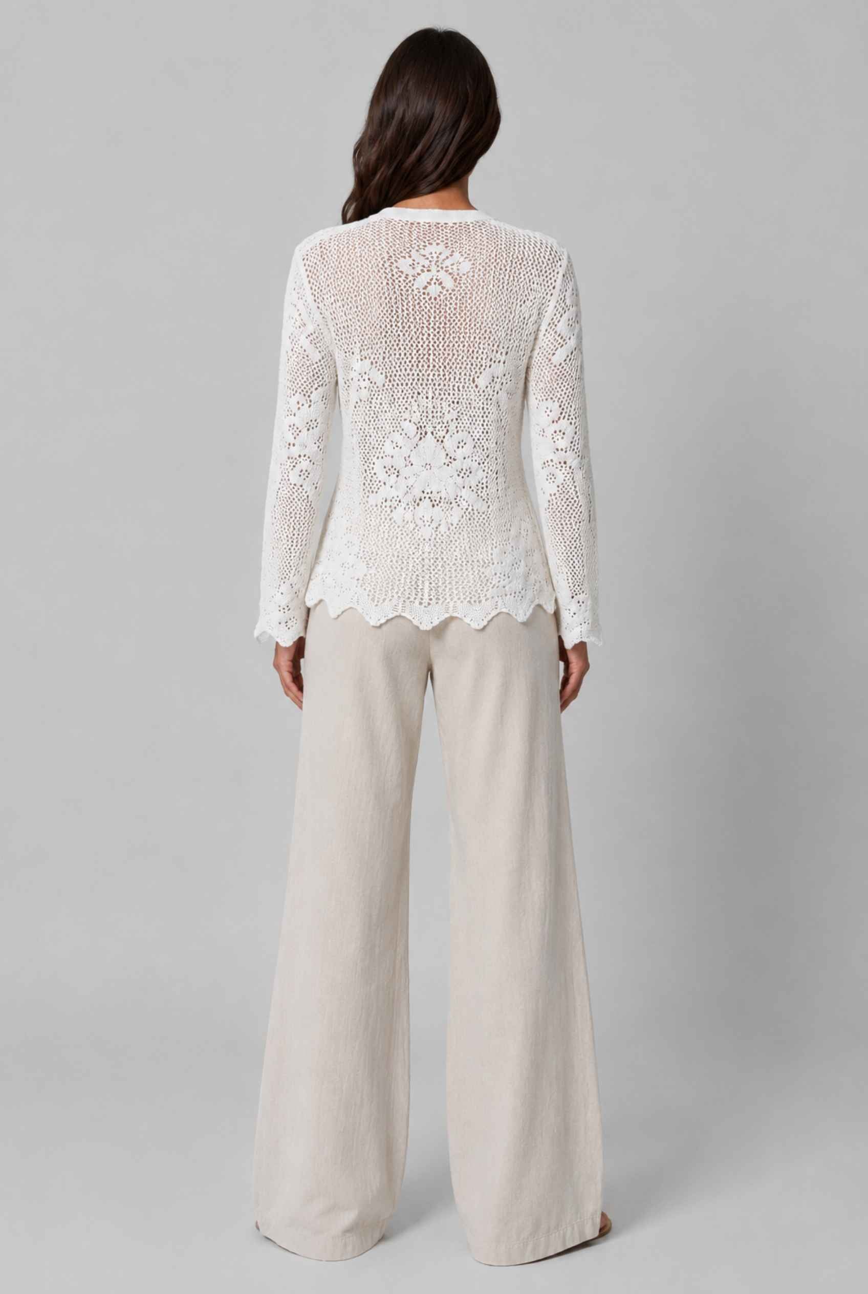 Woman wearing The Faye Tie-Front Cardigan Open Stitch White Crochet Cardigan on a gray background