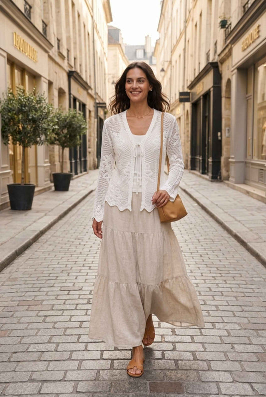 Woman wearing The Faye Tie-Front Cardigan Open Stitch White Crochet Cardigan paired with flowy skirt walking down a shopping street