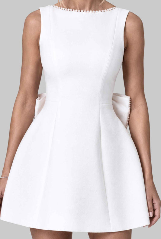 Virtual model wearing The Noemi Pearl Bow Dress Pearl-Trimmed Statement Bow Mini Dress in White