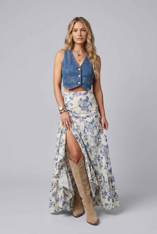 The Sonora Ruffle Skirt Blue Floral Flowy Skirt, and tan boots on a gray background