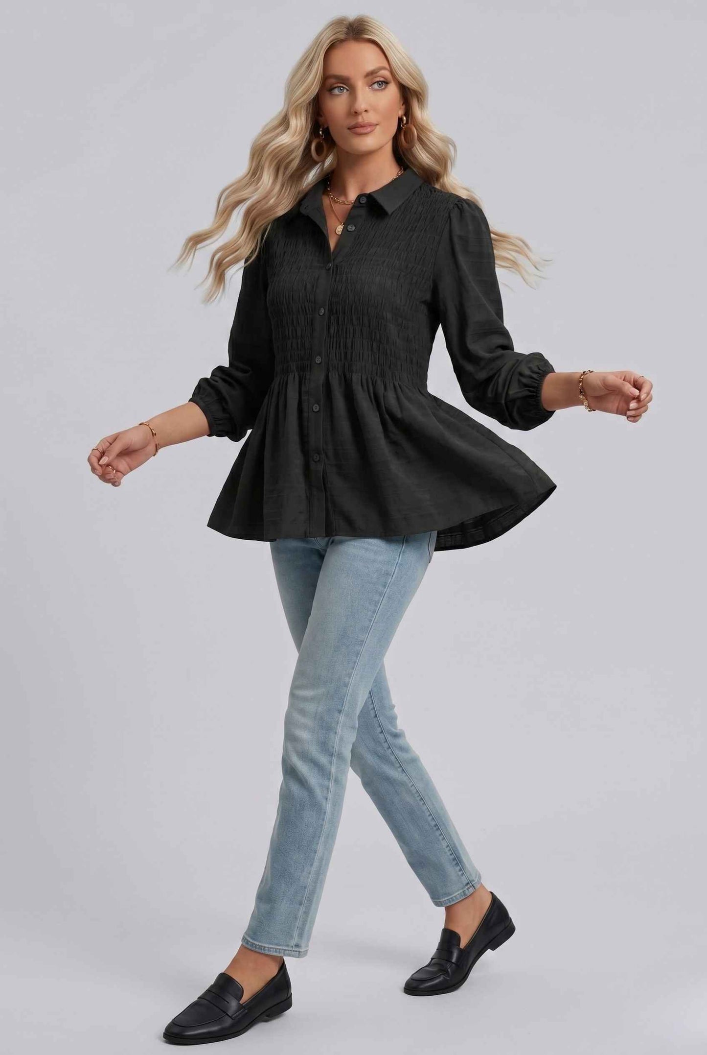 Woman wearing The Sutton Peplum Blouse Smocked Button-Down Black Top on a gray background