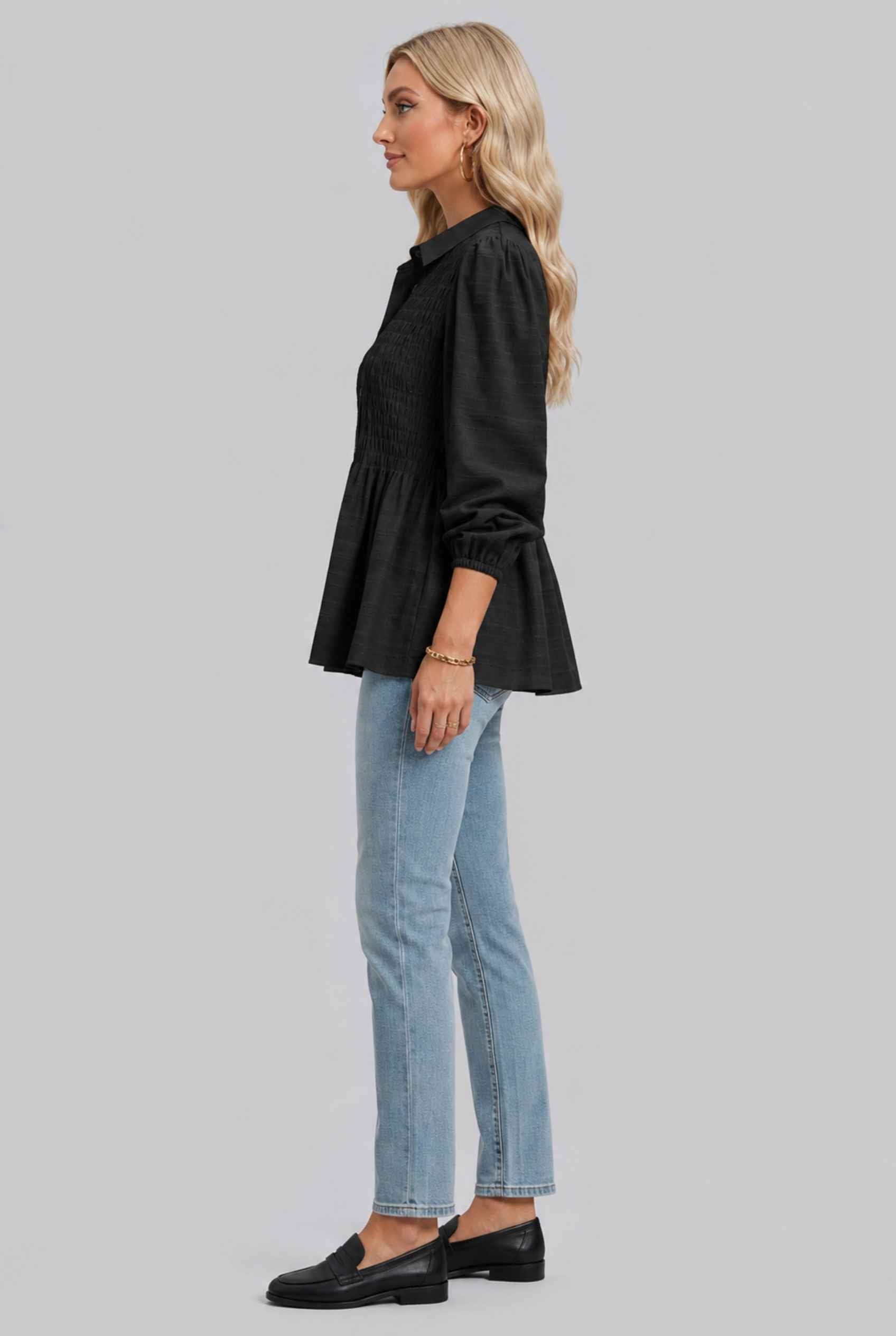 Woman wearing The Sutton Peplum Blouse Smocked Button-Down Black Top on a gray background