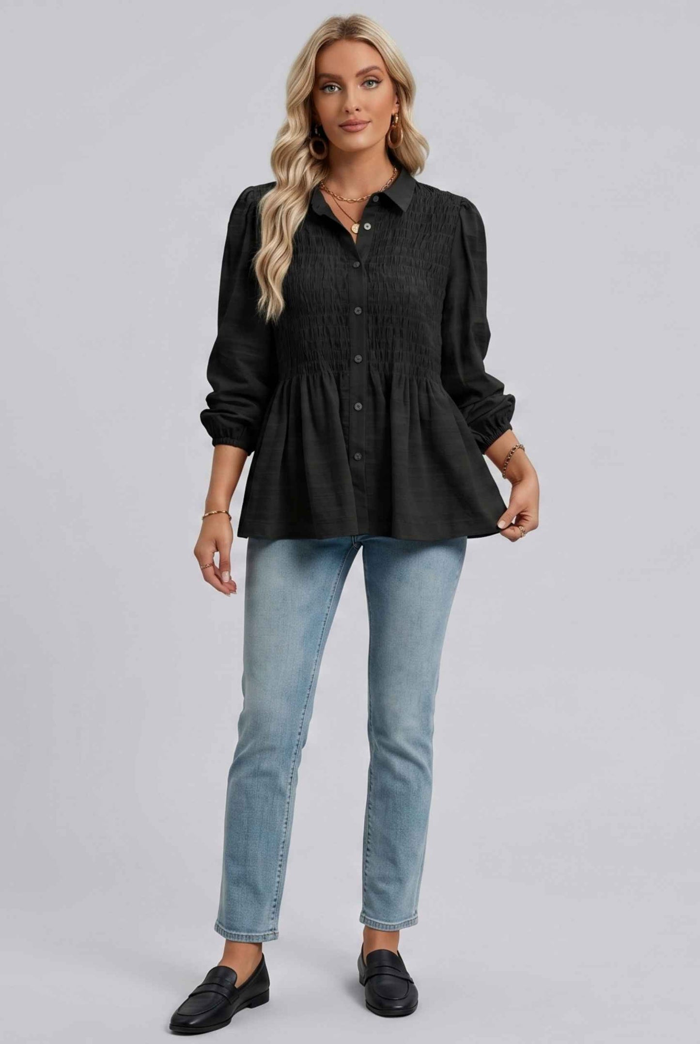 Woman wearing The Sutton Peplum Blouse Smocked Button-Down Black Top on a gray background