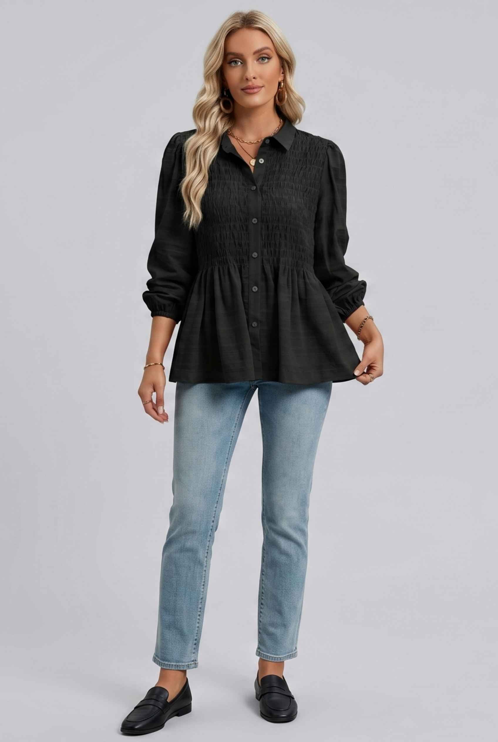 Woman wearing The Sutton Peplum Blouse Smocked Button-Down Black Top on a gray background