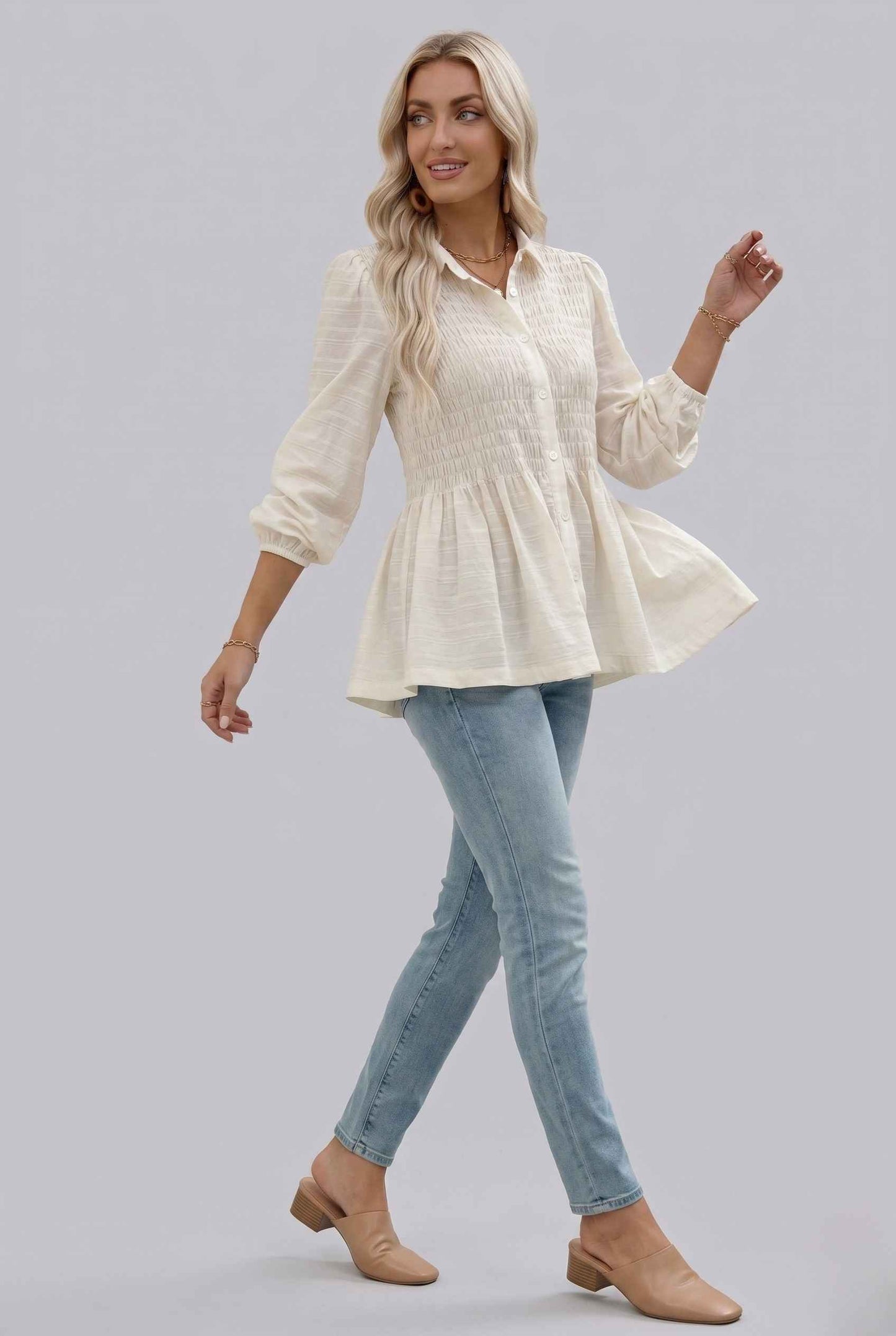 Woman wearing The Sutton Peplum Blouse Smocked Button-Down Off White Top on a gray background