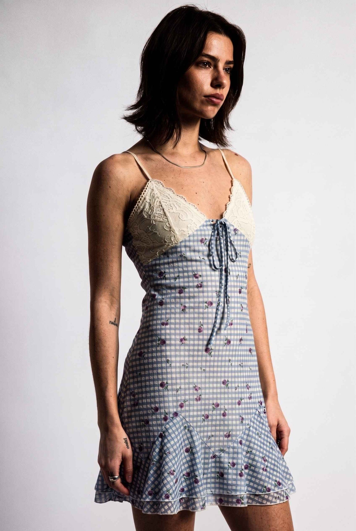 Model wearing Valencia Lace-Trim Gingham Mini Dress Floral Slip Dress in Blue close up side lace and tied detail