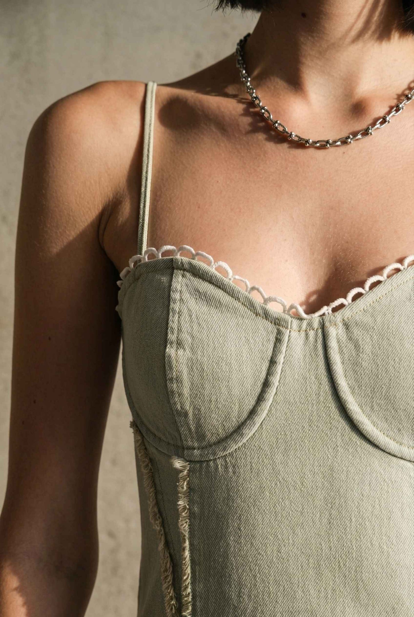 Model wearing Willow Mini in Light Green Denim with cotton tiers dress close up corset details