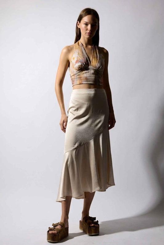 Model wearing Willow Skirt in Champagne Asymmetrical Ruffle Hem Midi Skirt paired with tie-back halter top and wedge sandals