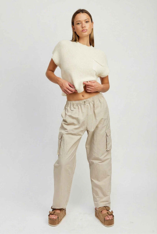 Model wearing Wren Pants 100% Nylon Parachute Cargo Pants in Taupe with t-shirt and platform sandals on plain background