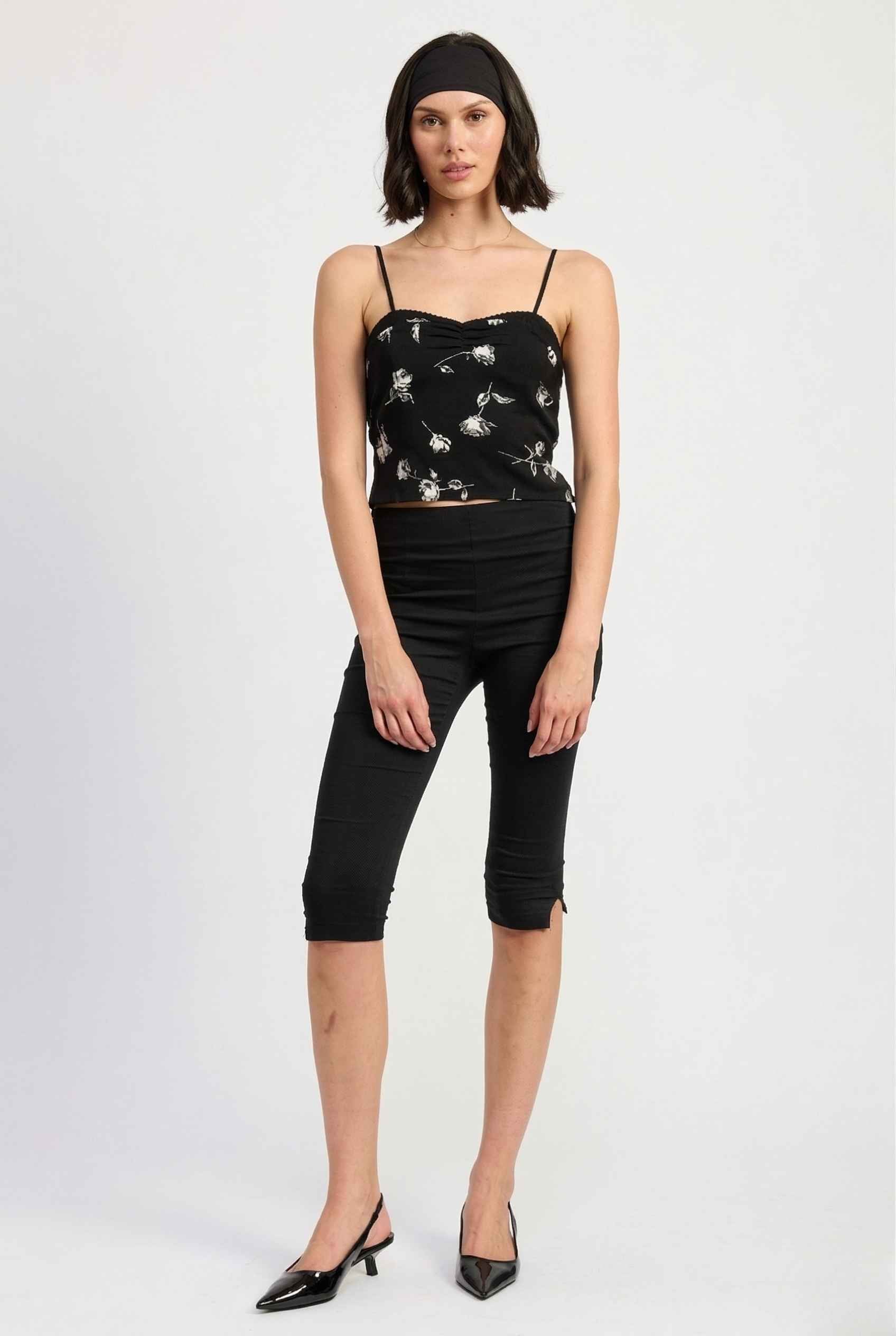 Woman wearing a Zara Top Black & White Rose Print Cotton Lace Trim Camisole and black pants on a white background