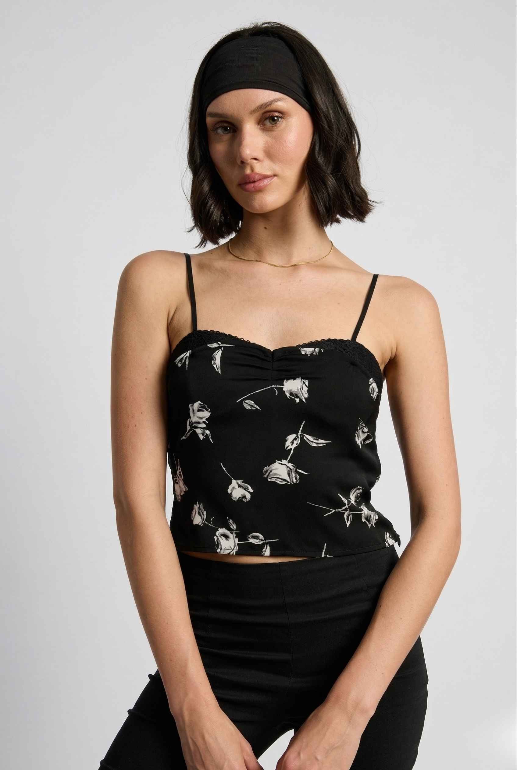 Woman wearing a Zara Top Black & White Rose Print Cotton Lace Trim Camisole against a plain background