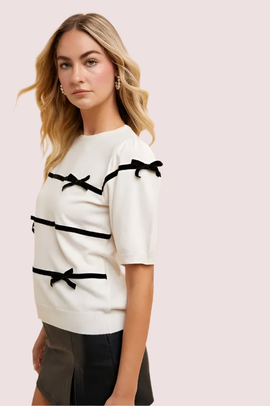 Annie Wear Striped Bow Round Neck Knit Top featuring stylish black bows on a cream background
