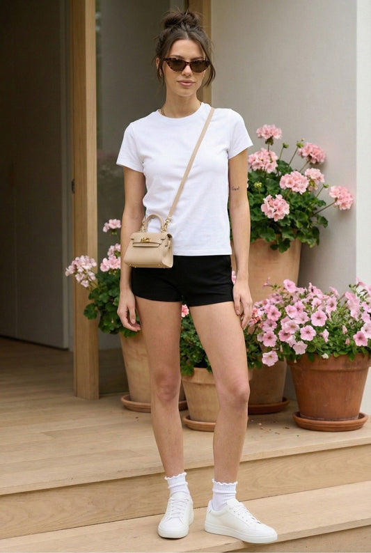 Model wearing Emory Park Biker Mini Shorts in Black with basic t-shirt sneakers standing on front doorstep with flowers