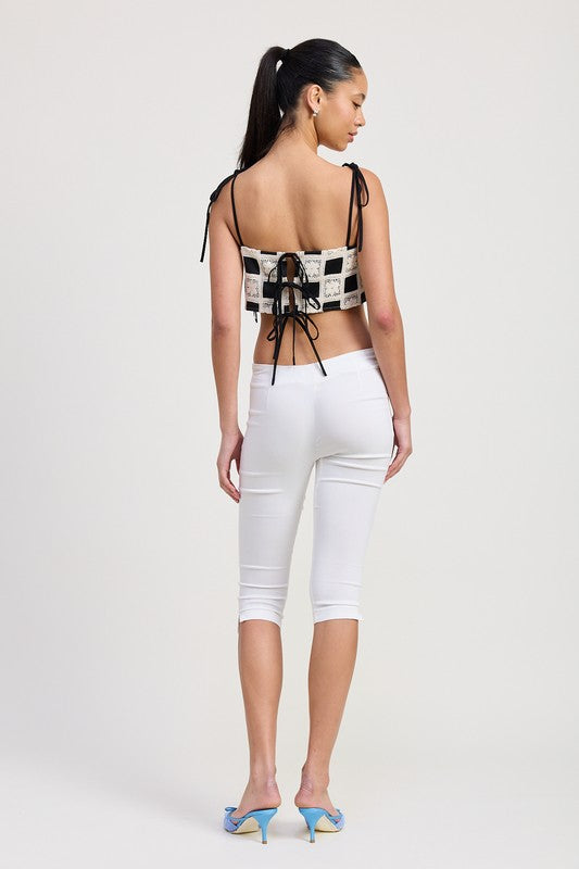 Back view of woman wearing Emory Park black and white Cropped Crochet Top with lace-up detail and white capri pants