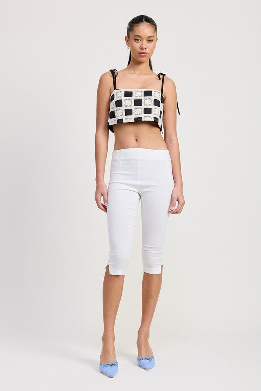 Model wearing Emory Park cropped crochet top with black and white checkered pattern and white capri pants