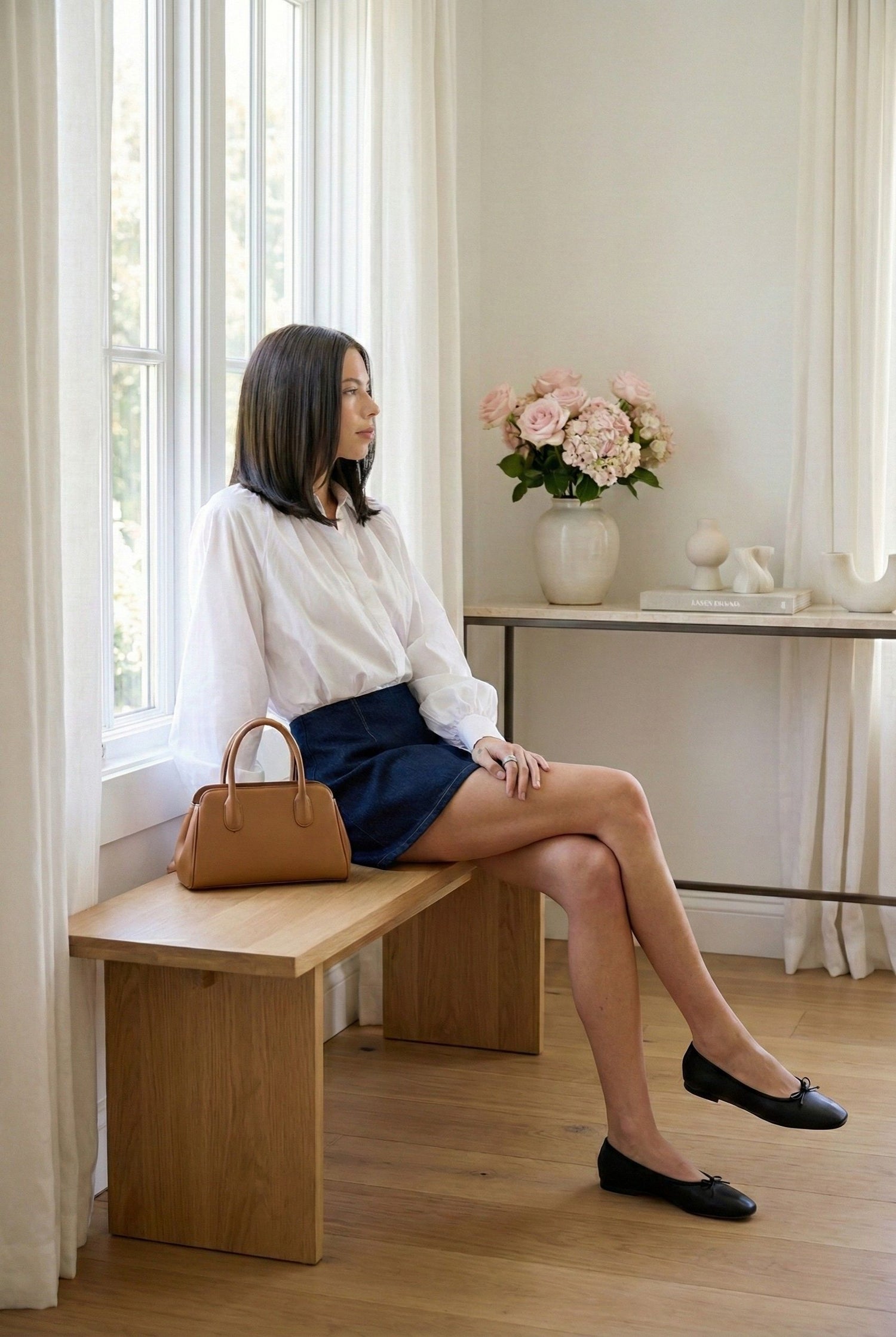Model wearing Emory Park Dark Denim Skort With Elastic Waistband with blouse and flats sitting in luxury minimalist home