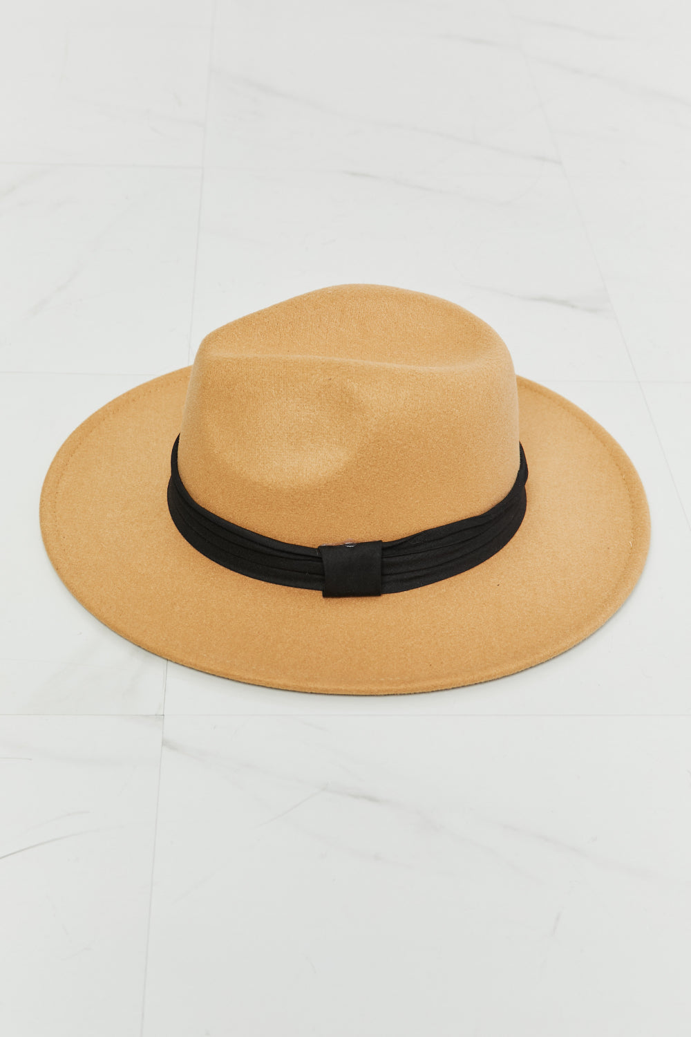Fame You Got It Fedora Hat in tan with black ribbon band lying on white marble surface