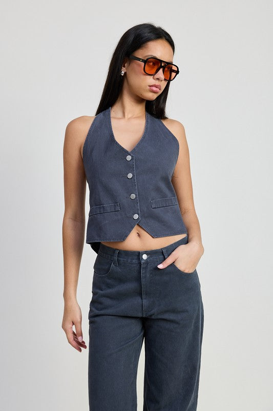 Woman wearing dark folded fitted denim pants with buttoned sleeveless vest and orange sunglasses by Emory Park