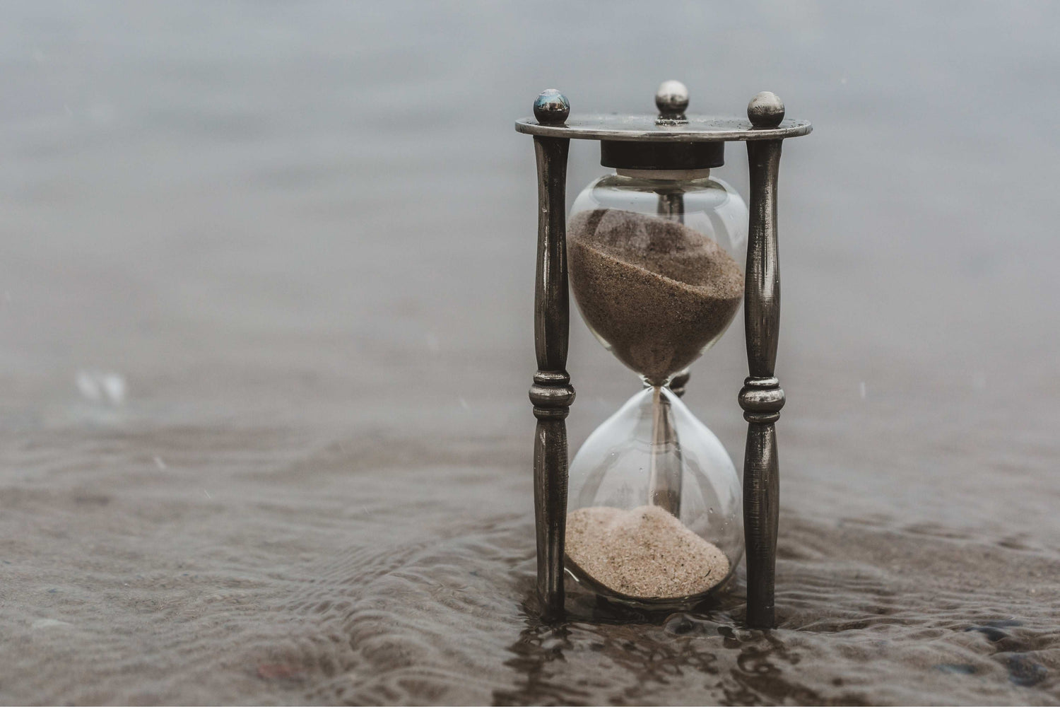 Hourglass with sand running through on a wooden surface