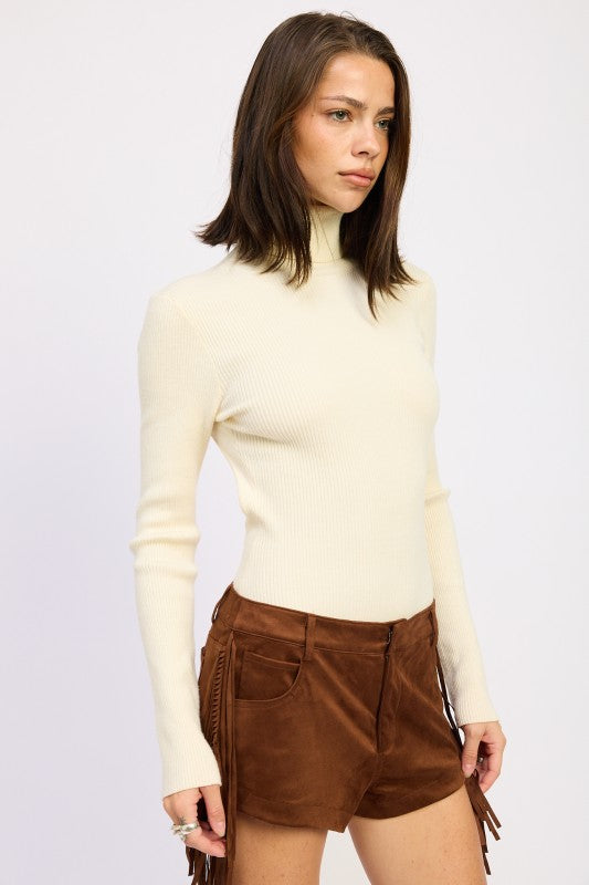 Emory Park Long Sleeve Turtle Neck Bodysuit in cream, paired with brown suede shorts for a stylish look