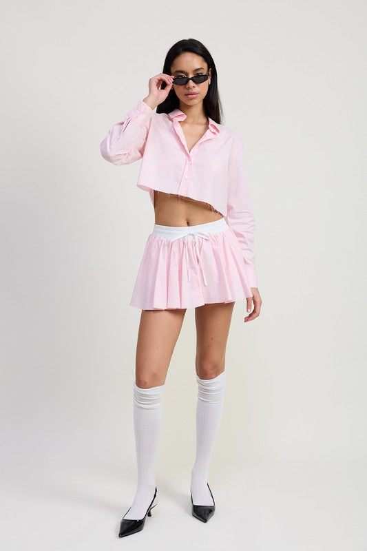 Woman wearing Emory Park pink mini contrast waistband skirt paired with a cropped button-up shirt and knee-high socks