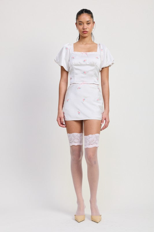 Emory Park Mini Satin Bias Skirt in white with pink floral print worn with puff sleeve top and lace thigh high stockings