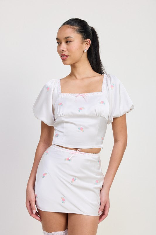 Emory Park Mini Satin Bias Skirt in white with small floral design worn with puff sleeve crop top