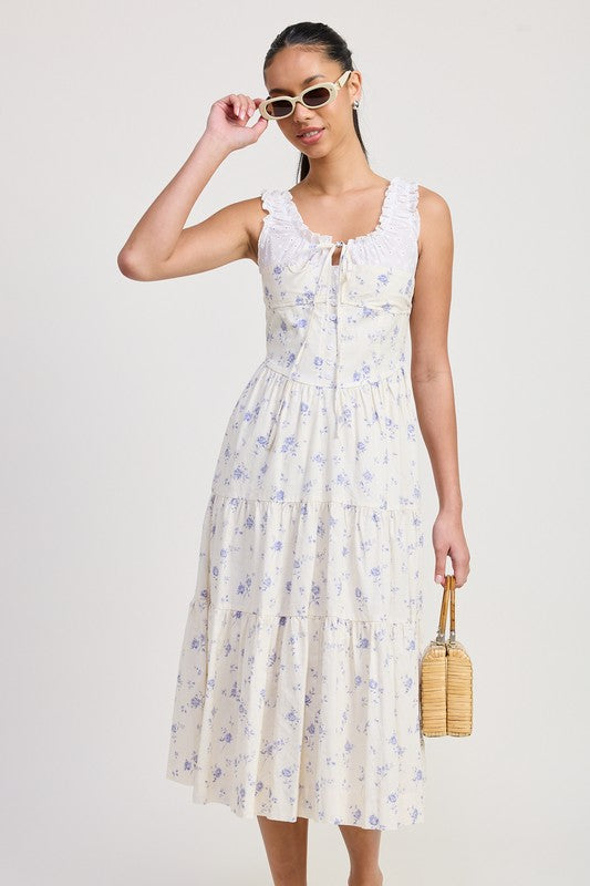 Woman wearing Emory Park Mixed Media Eyelet Peekaboo Midi Dress with floral pattern and ruffle neckline holding a woven handbag