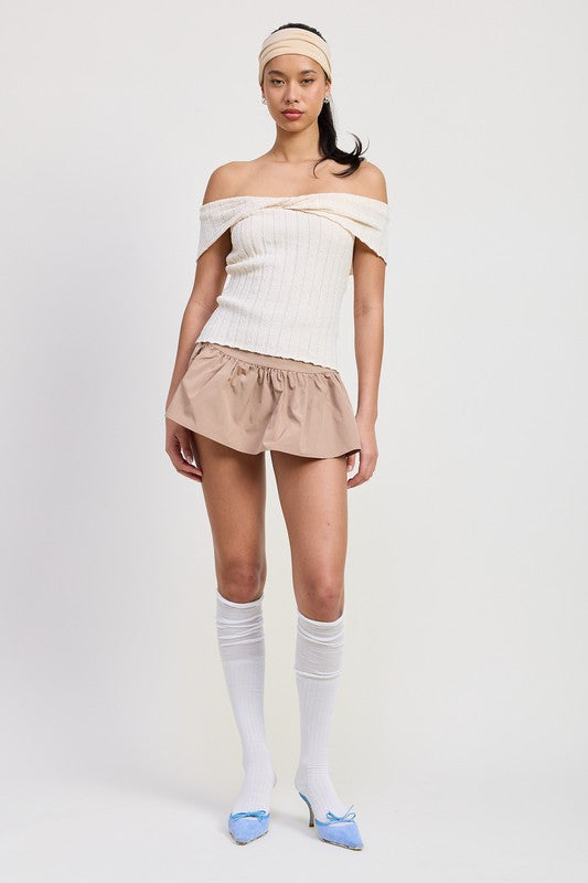 Woman wearing Emory Park off shoulder sweater top in white with beige shorts and blue heels