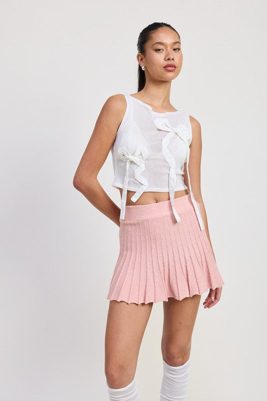 Emory Park pink pleated mini skirt worn with white sleeveless top and knee-high socks