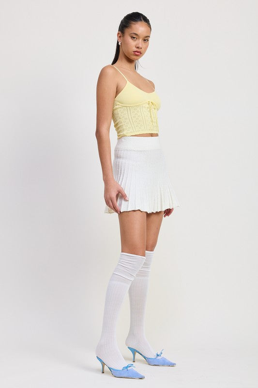Emory Park white pleated mini skirt worn with yellow top and blue heels with white knee-high socks