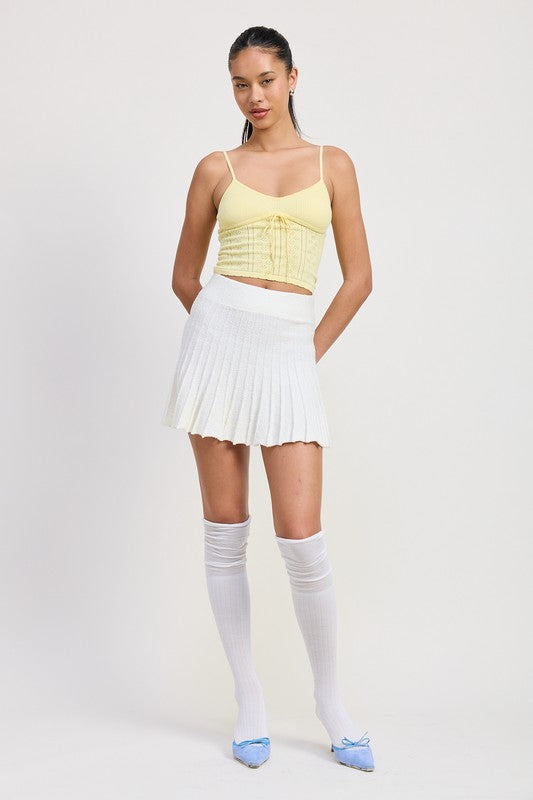 Emory Park white pleated mini skirt worn with a yellow cropped top and knee-high white socks